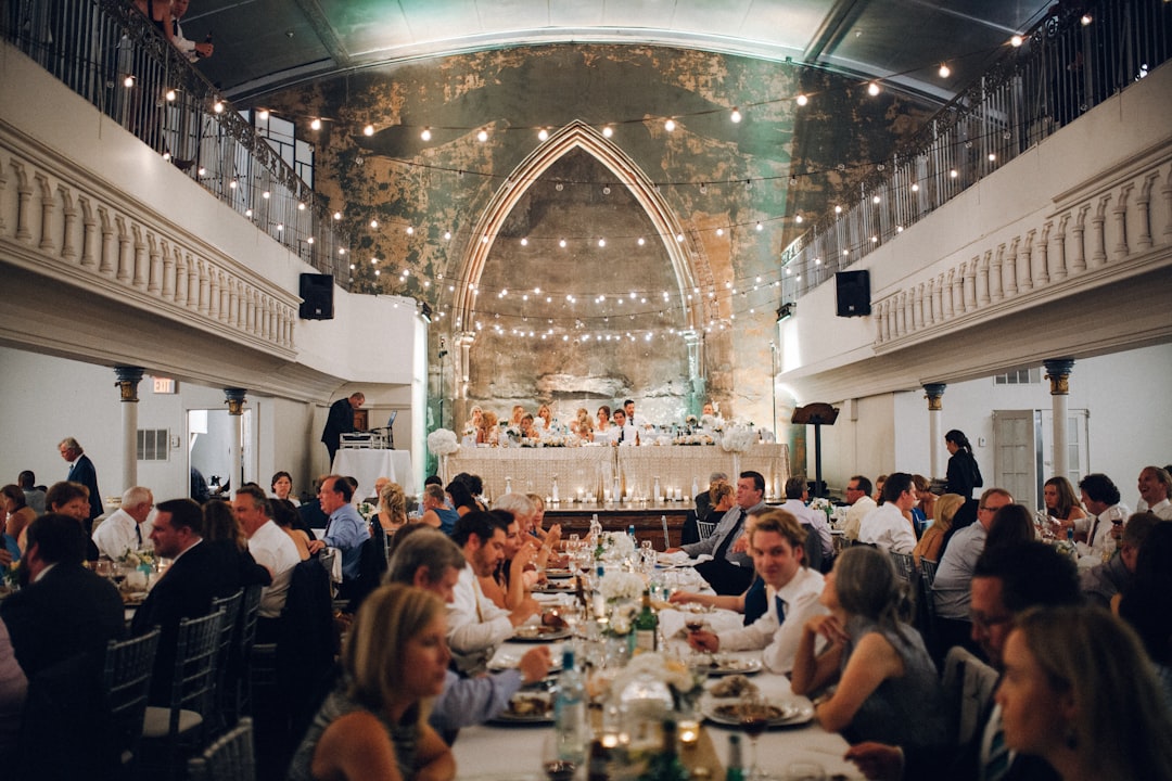 Guests enjoying a wedding reception dinner in a beautifully lit, spacious hall