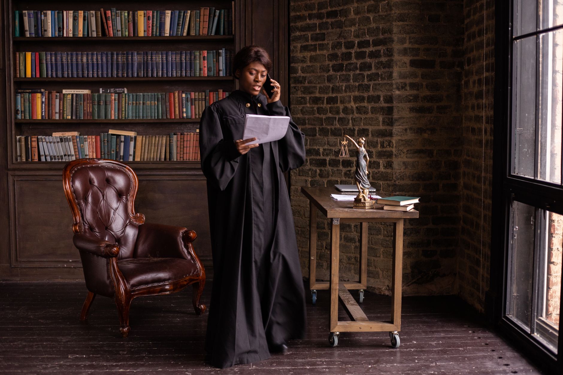 Female lawyer in black robe talking on phone, holding documents, in an office