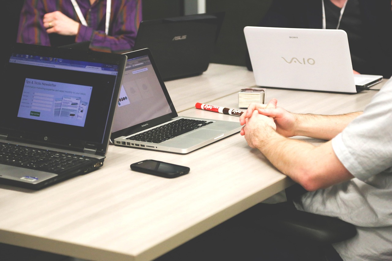 People sitting at a table with laptops open, one showing a newsletter signup form