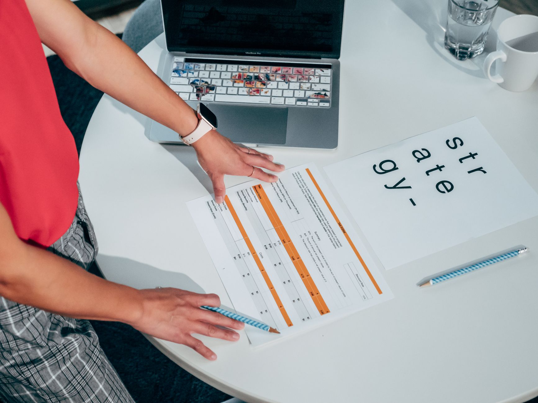 Hands on a report and "strategy" paper with a laptop on a white table