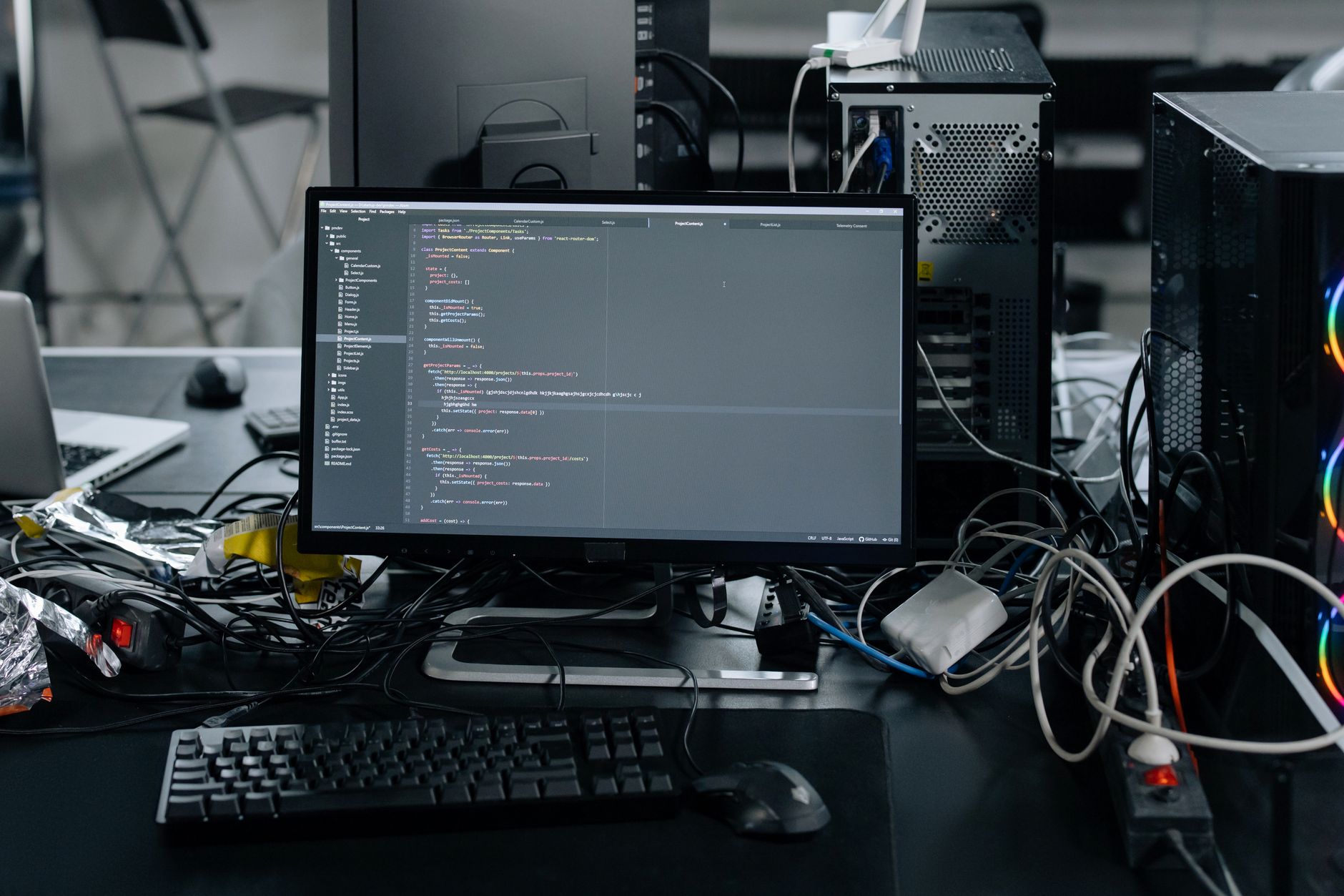 A computer monitor displays programming code, surrounded by development workstation hardware