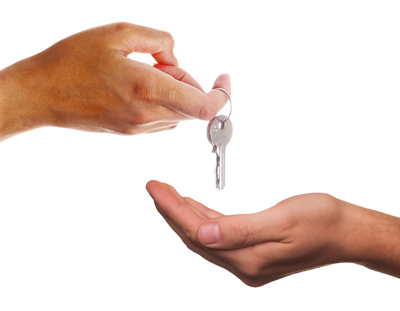 A hand handing over a house key to another open hand, signifying handover
