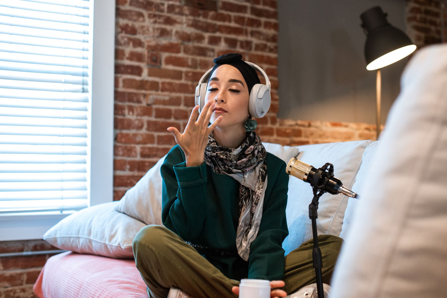 Woman wearing headphones records a beauty podcast while applying a skincare product