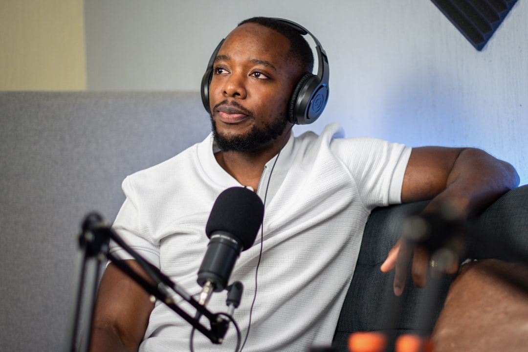 Man wearing headphones and a white shirt records a podcast with a microphone
