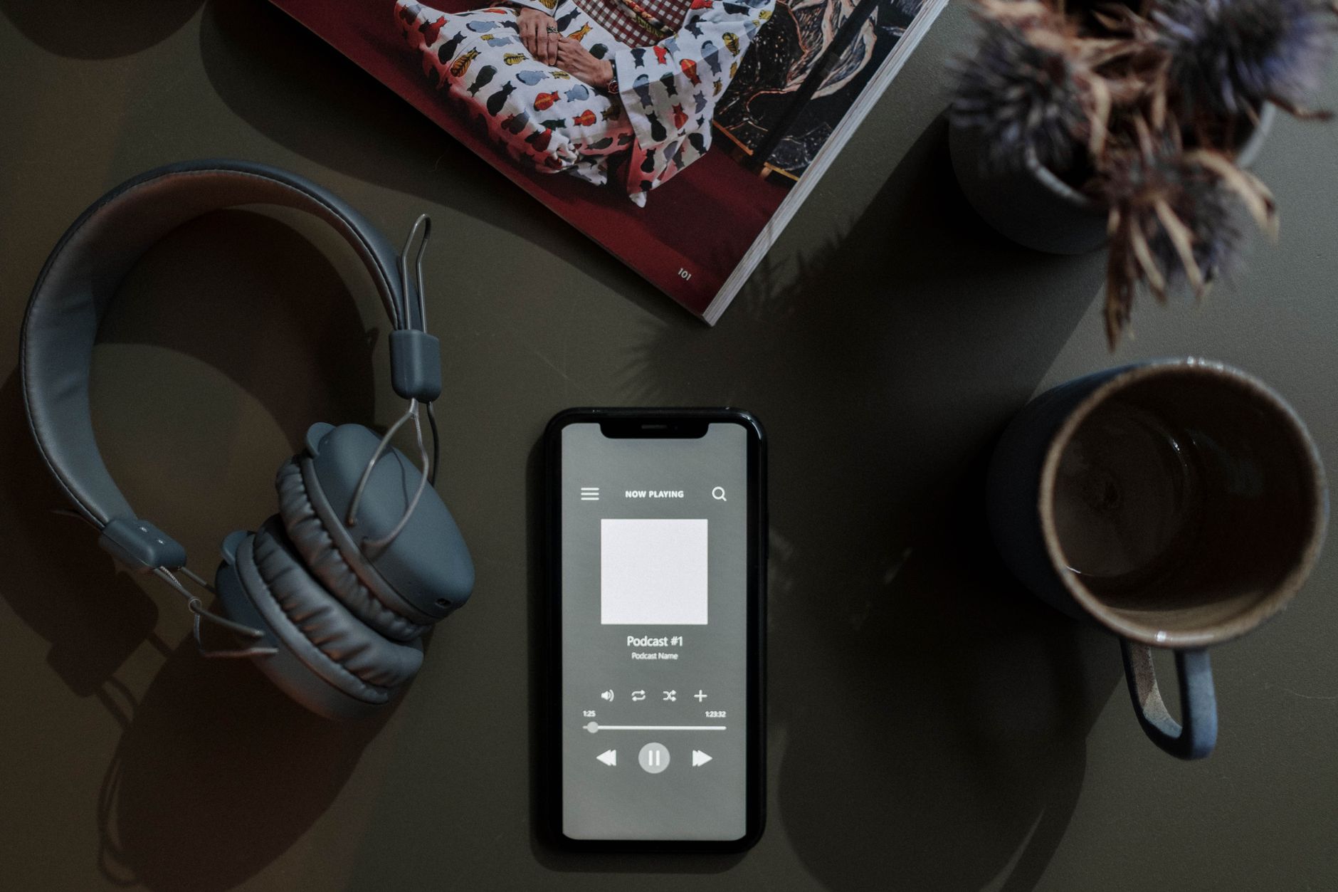 Smartphone displaying a podcast player next to headphones, illustrating audience measurement