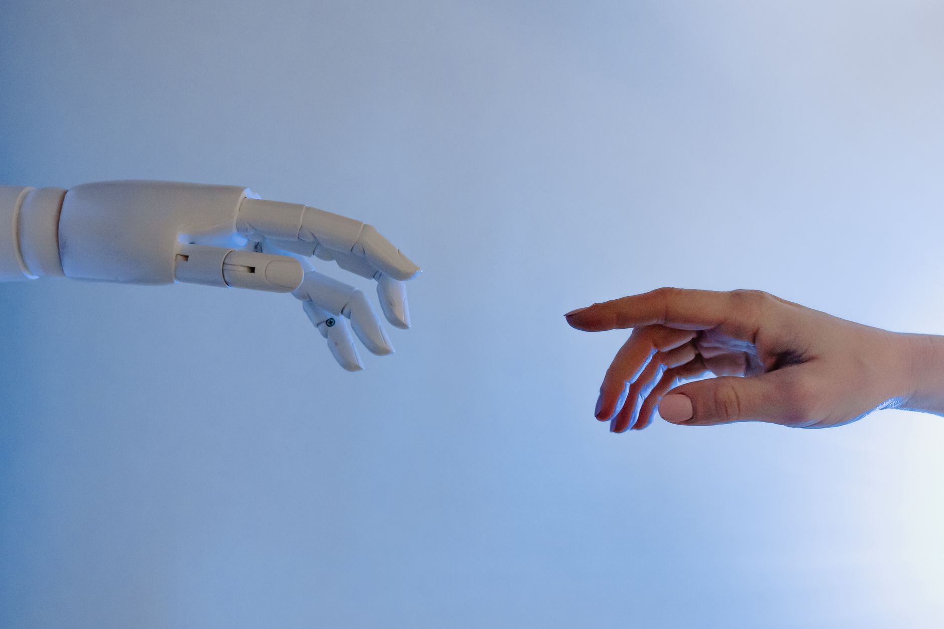 Robotic hand and human hand reaching out, symbolizing AI interaction and ethics