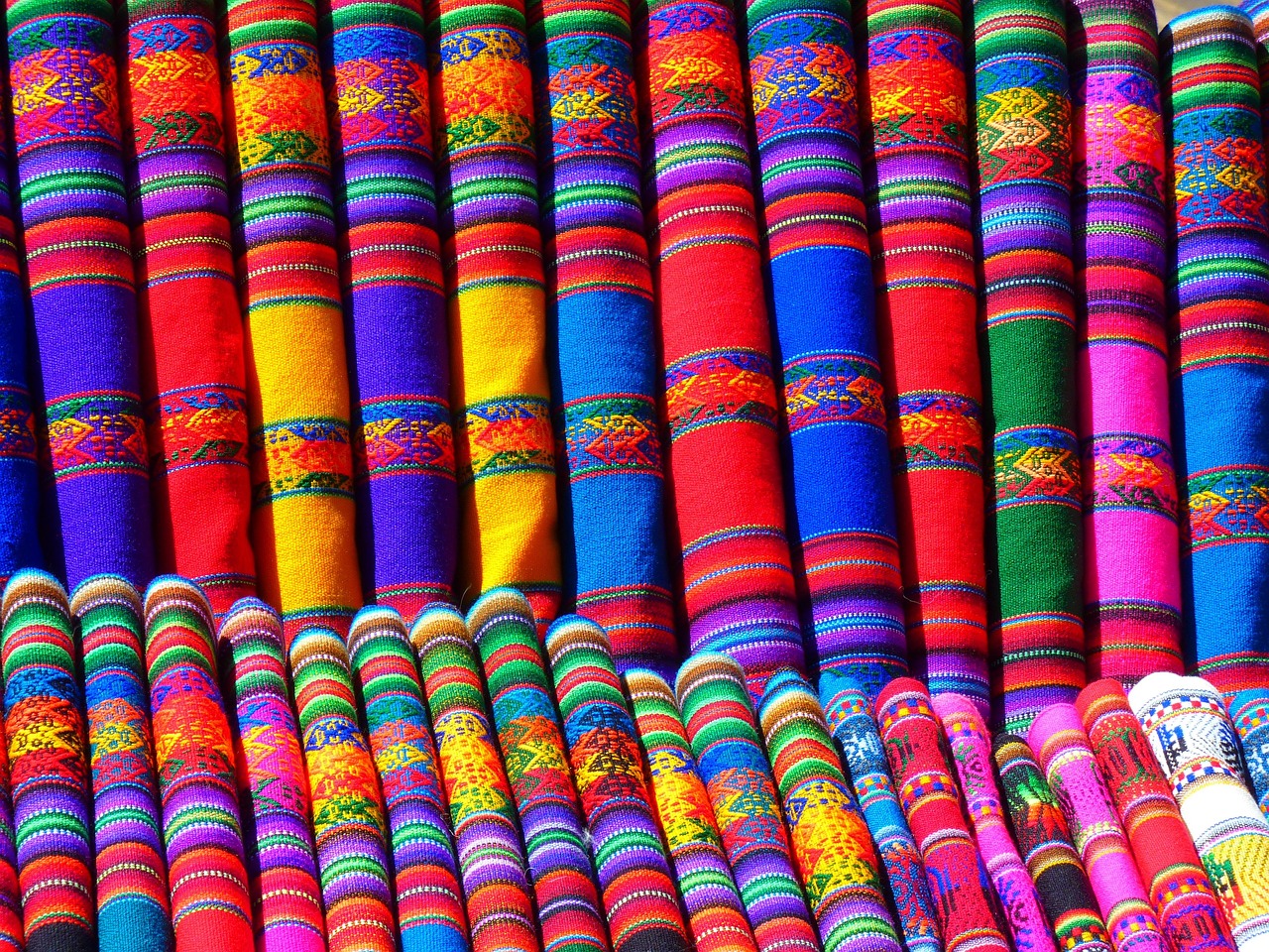 Rolled-up fabrics with bright colors and geometric patterns in two rows