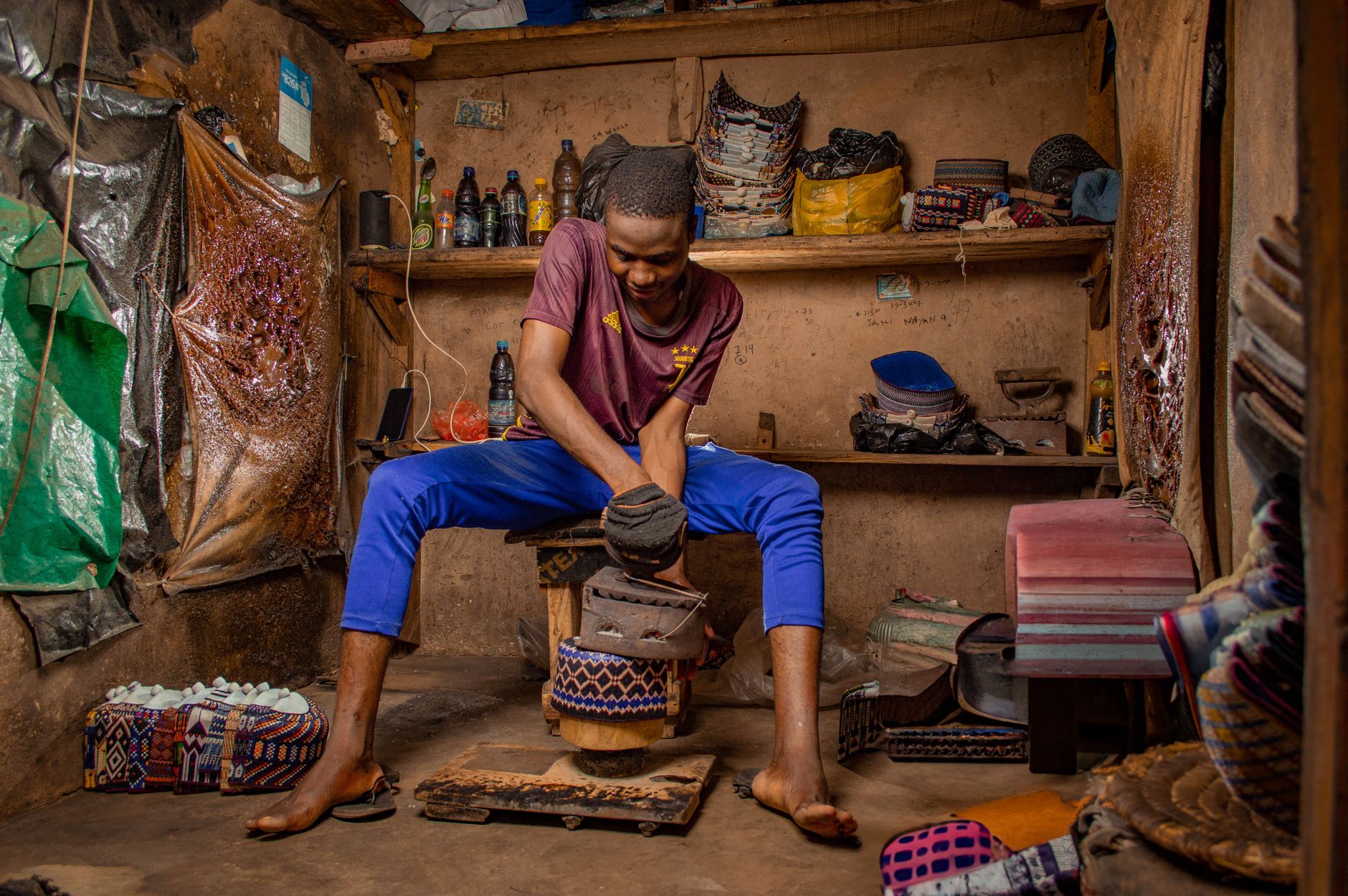 A Nigerian artisan shapes a cap using an old iron in a traditional workshop