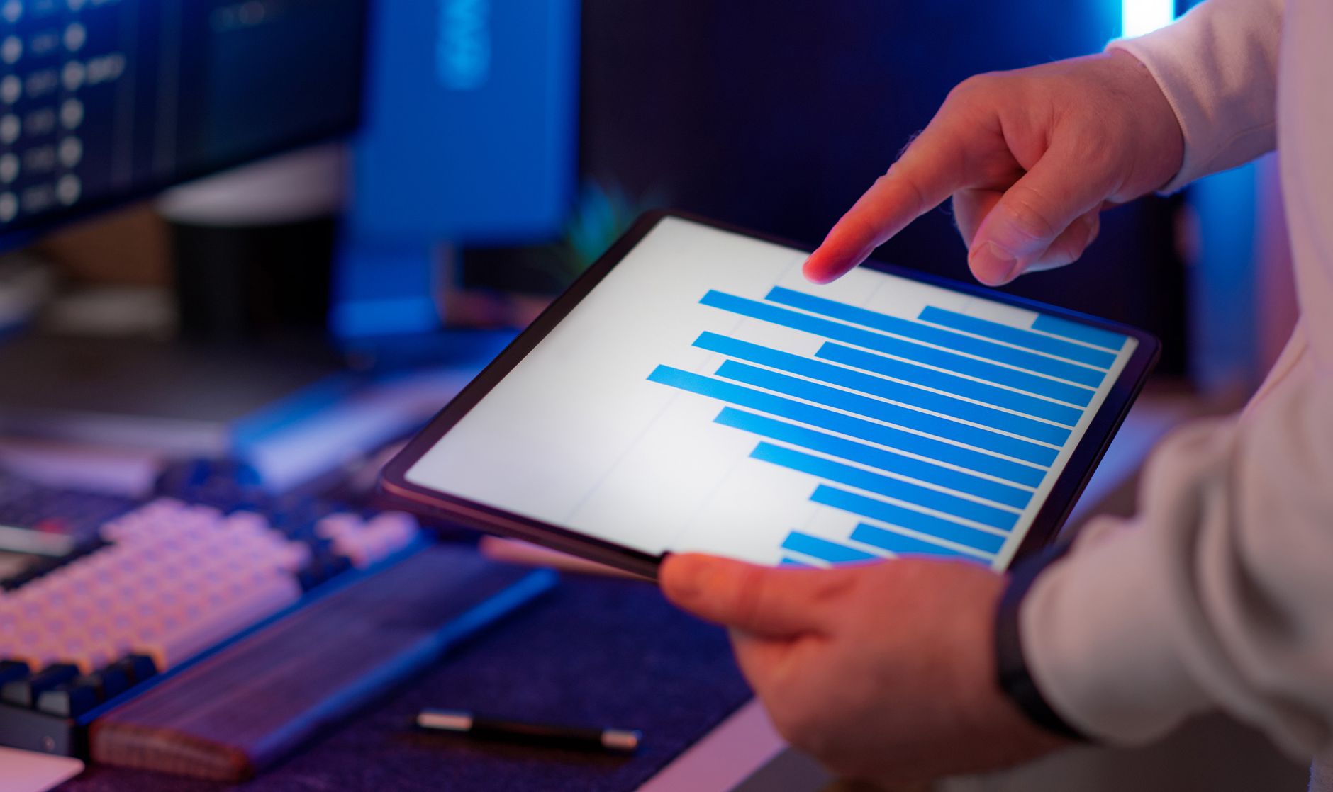 Hand pointing at a tablet displaying a bar chart of website analytics data