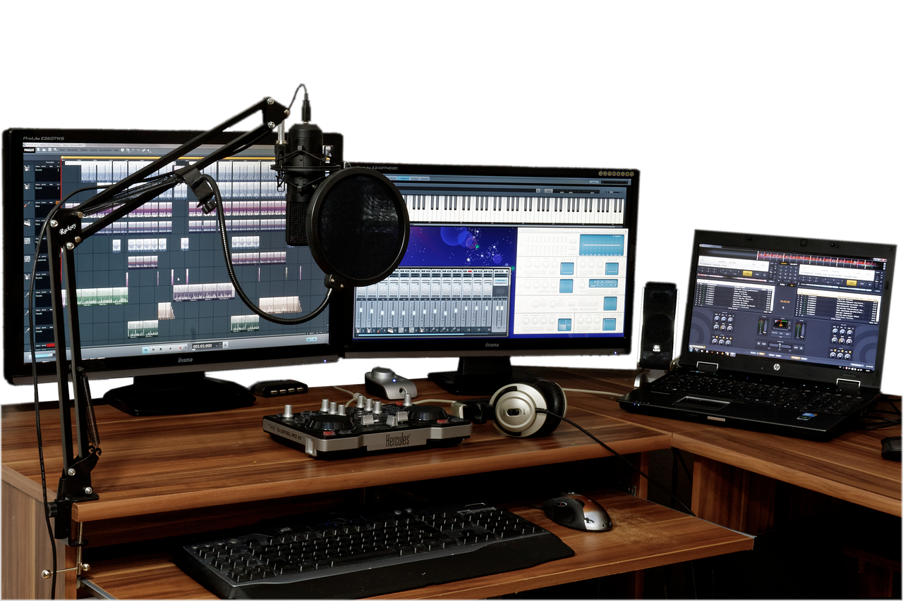 A microphone, headphones, and computer screens display audio editing software on a desk