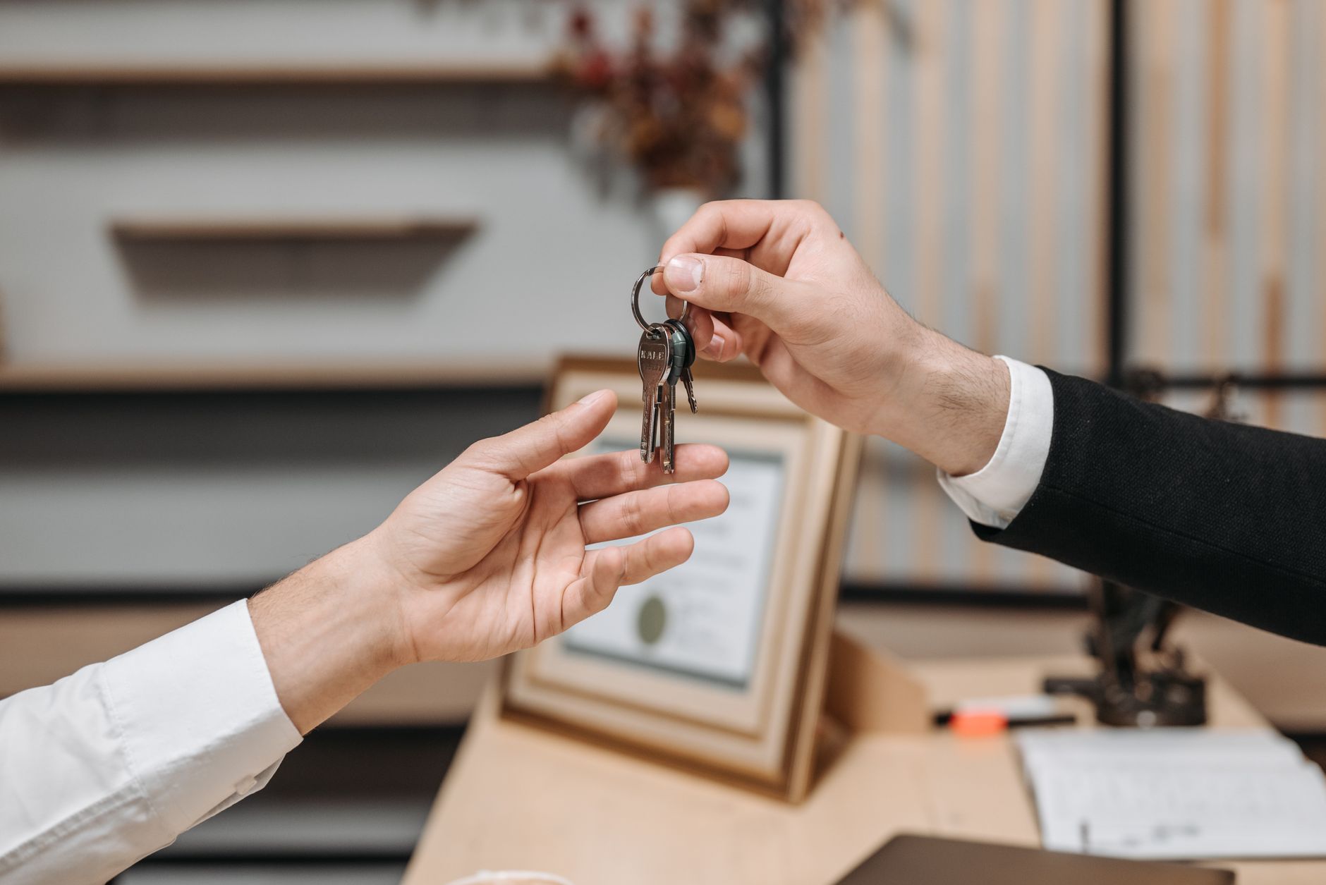 One hand gives keys to another, symbolizing contract fulfillment or transfer