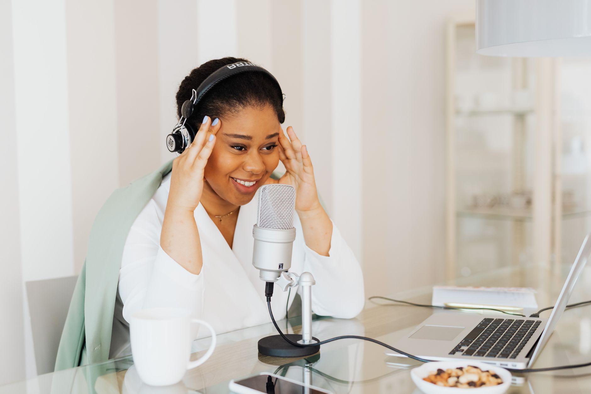 Smiling woman wearing headphones and speaking into a microphone at a desk