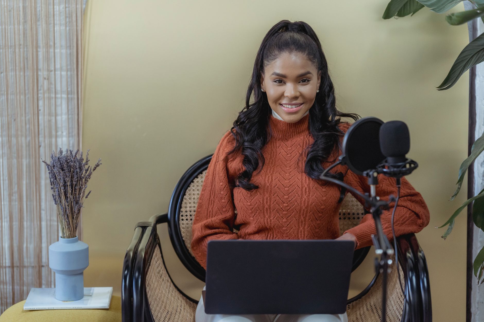 Smiling woman podcasting with a microphone and laptop, ready to record