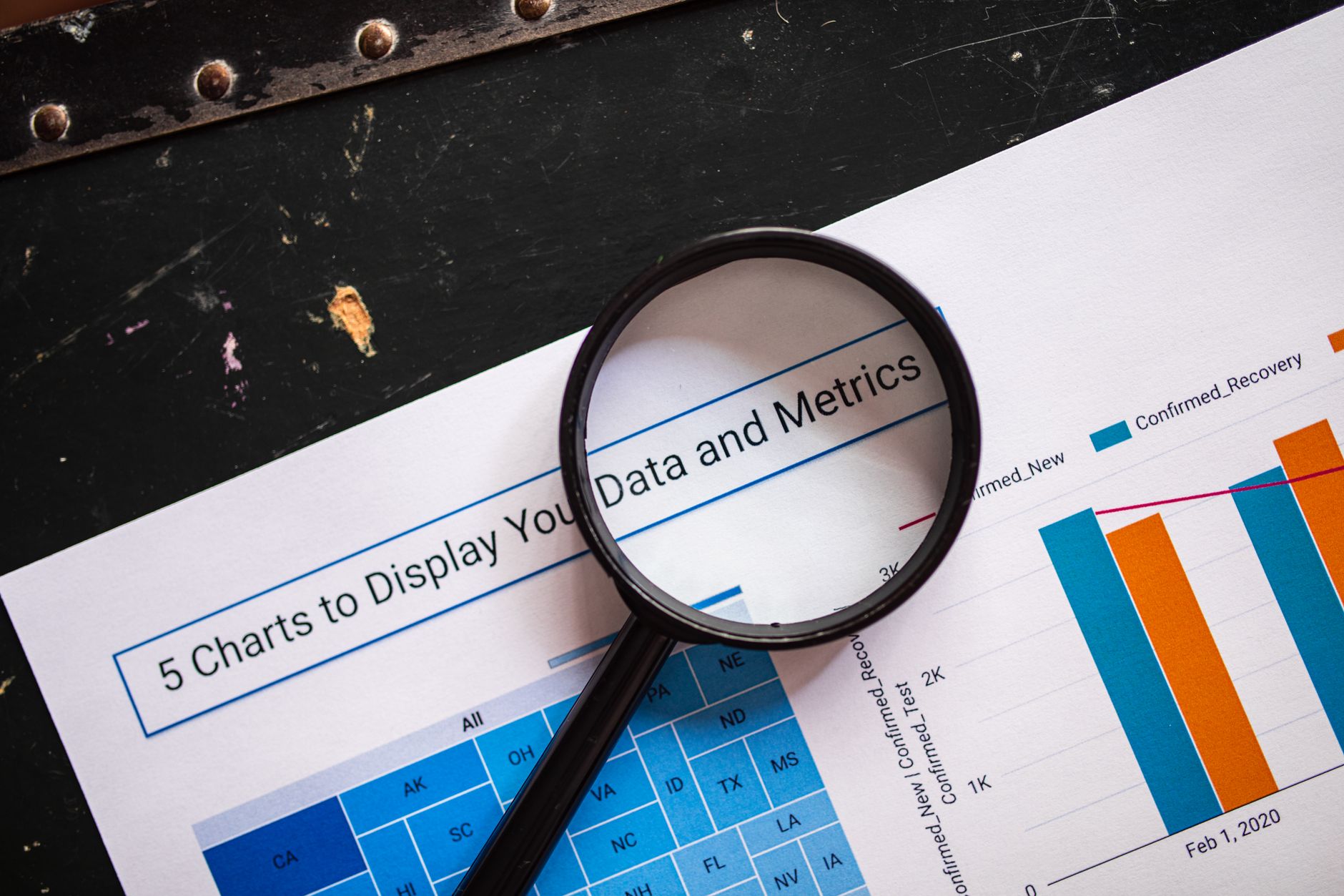 A magnifying glass examines charts and text titled "Data and Metrics" on a document