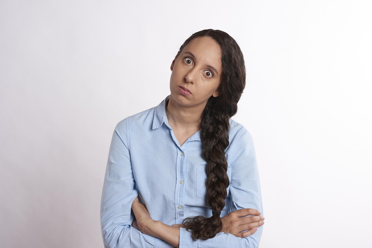 Woman with wide eyes and a skeptical expression, wearing a blue shirt and braid
