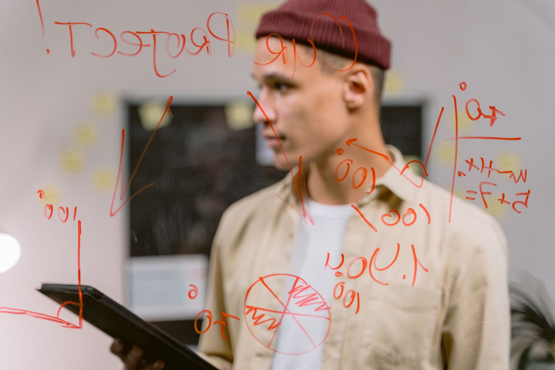 A man stands behind a glass board covered with red marker notes