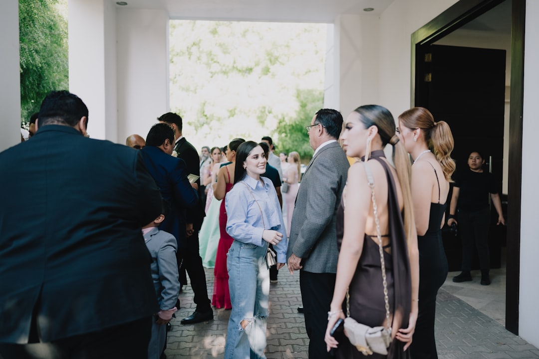Guests gather at an indoor-outdoor event entrance, some dressed formally, others casually