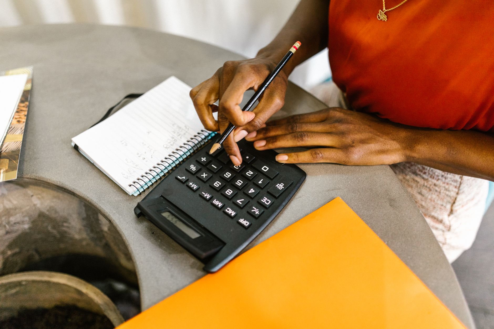A person's hands use a calculator and pencil while budgeting an event