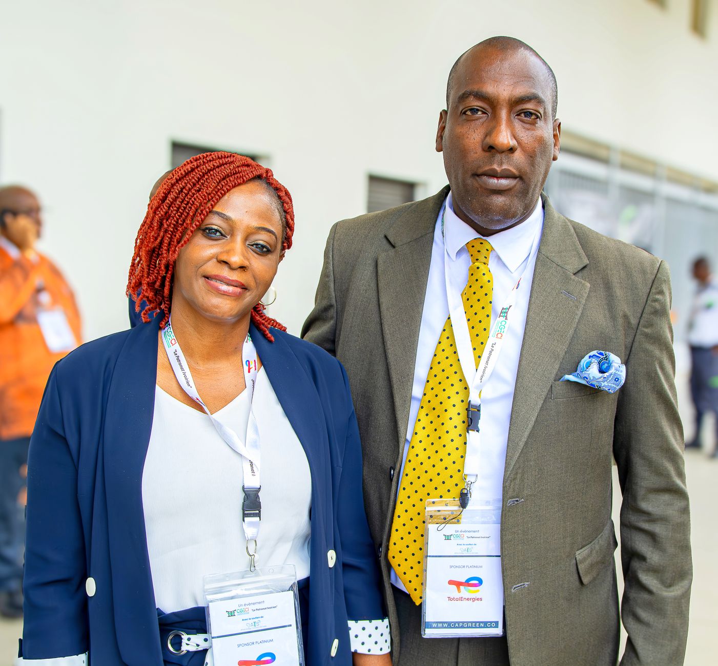 Two event attendees wearing lanyards and formal attire at a corporate function