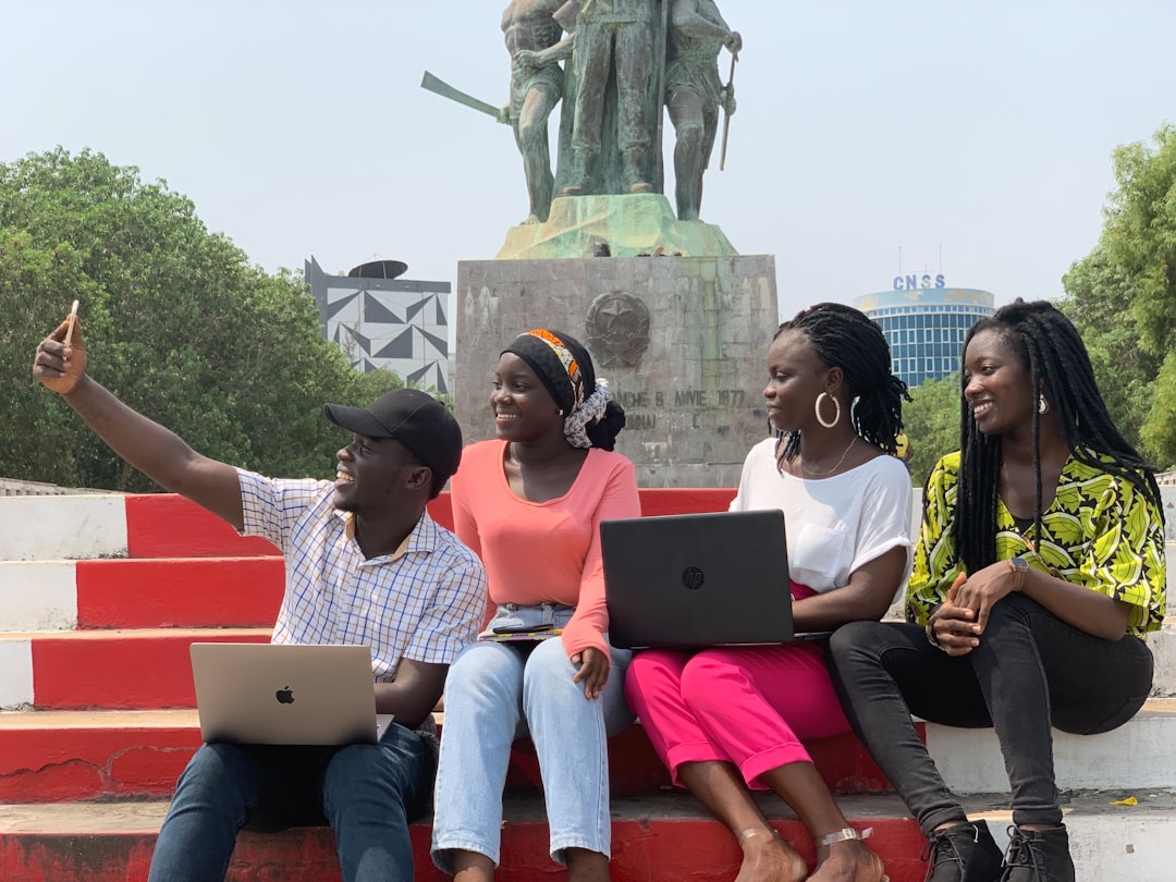 Four young Nigerians with laptops and phones working or studying outdoors
