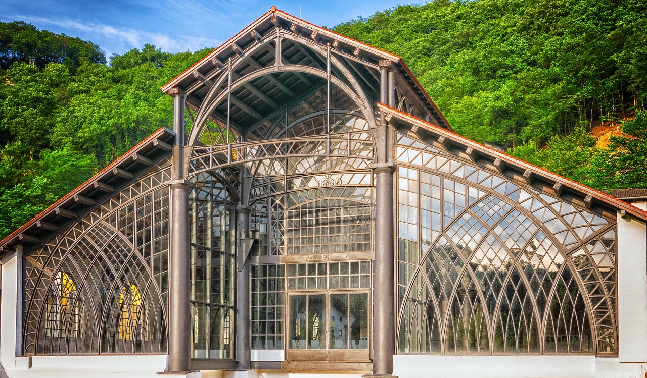 A distinctive Victorian-era glasshouse with a green forest in the background