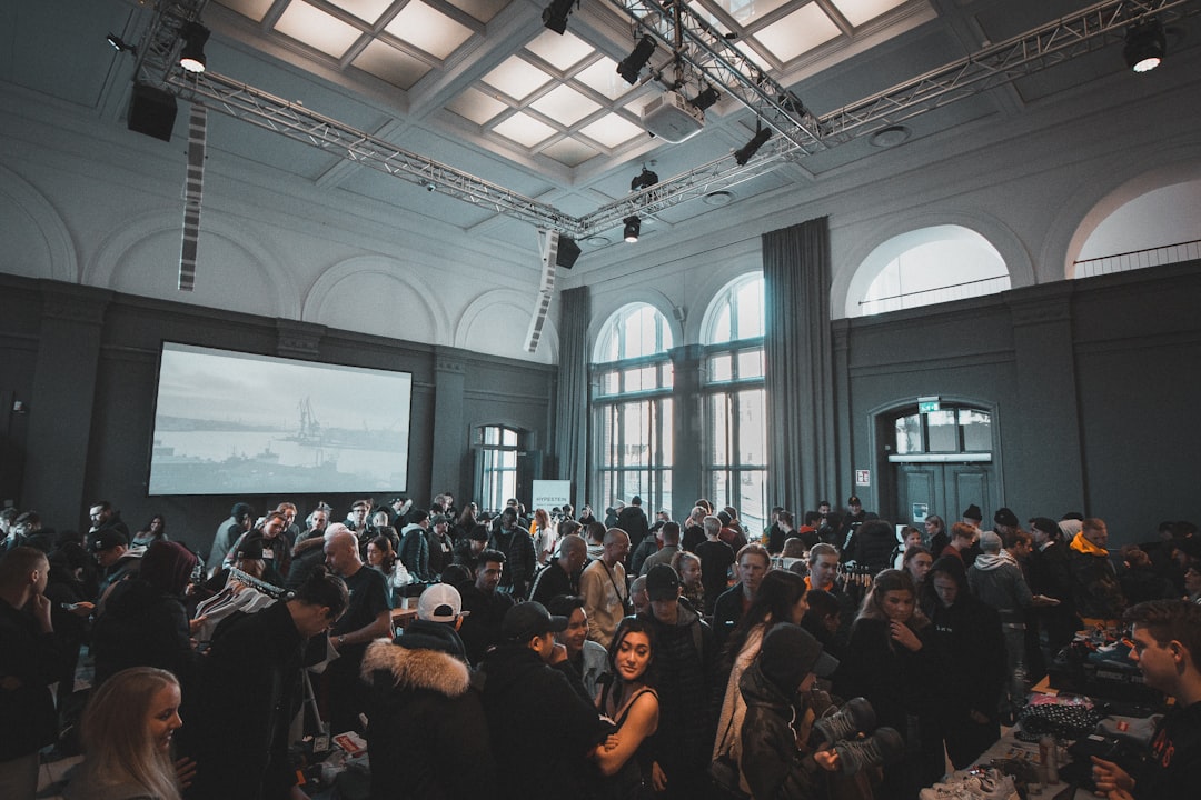 A large crowd gathers in a spacious hall with high arched windows