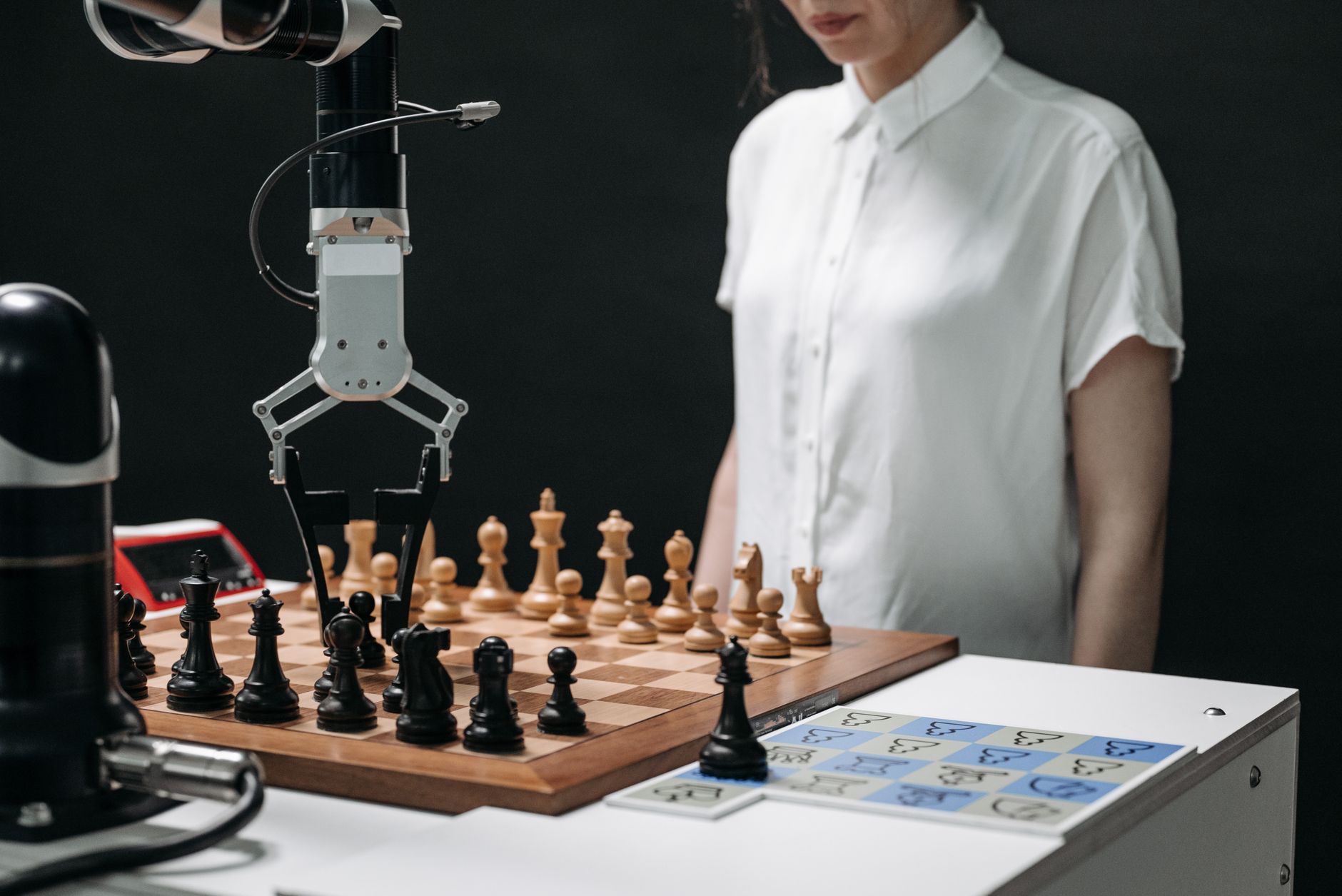 A robotic arm plays chess with a person, illustrating AI interaction and strategy