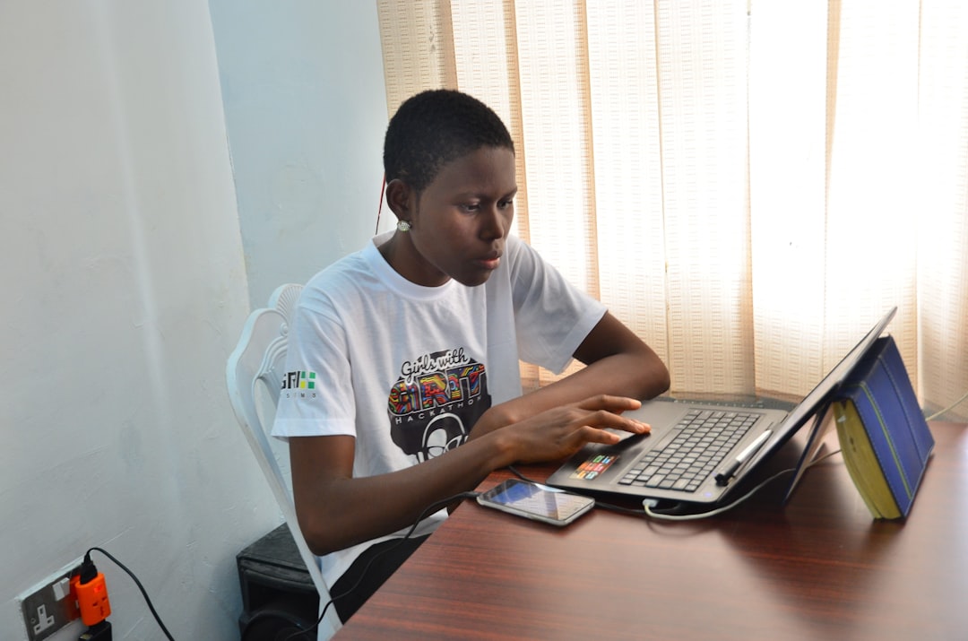 Young person typing on a laptop at a desk, researching business names