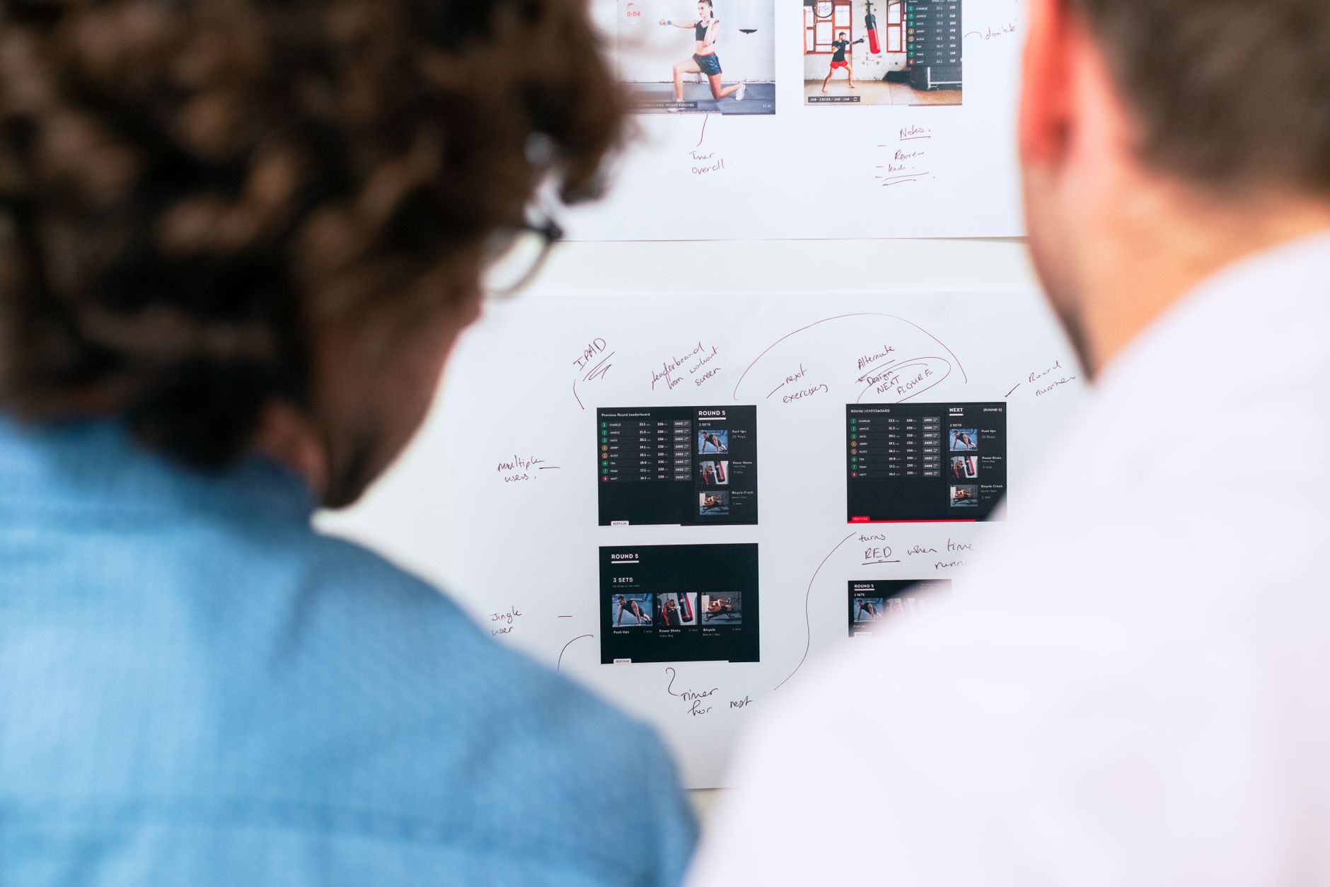 Two developers analyze workout app mockups and notes for website development