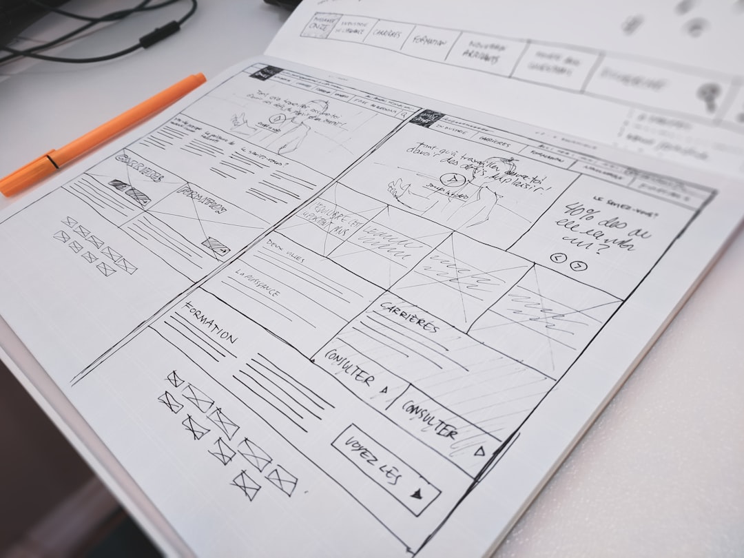 Hand-drawn website wireframes and layout sketches in a notebook with an orange marker