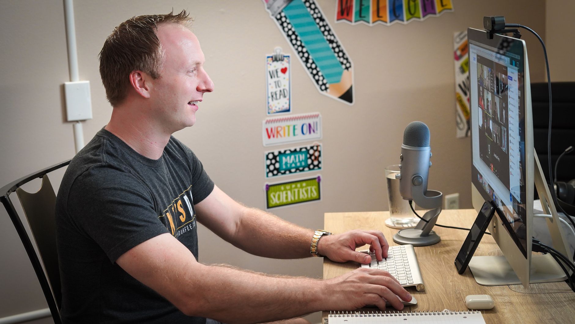Man on a video call at a desk with a microphone and computer