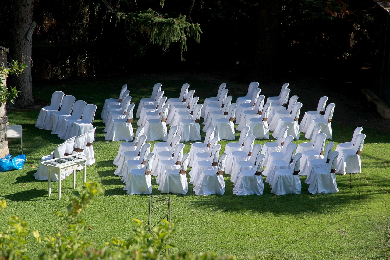 Rows of white chairs with brown sashes arranged on a green lawn for an event