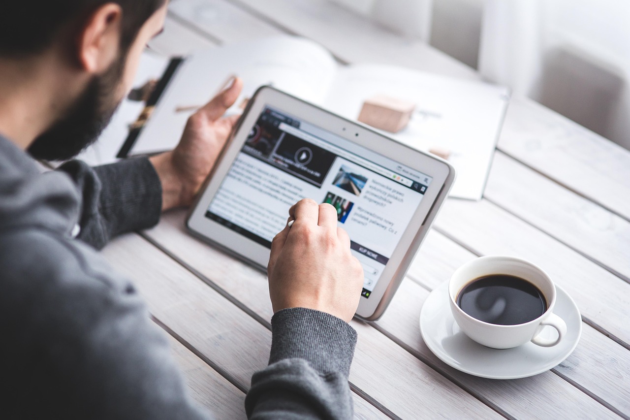 Person viewing digital content on a tablet with a stylus and a cup of coffee