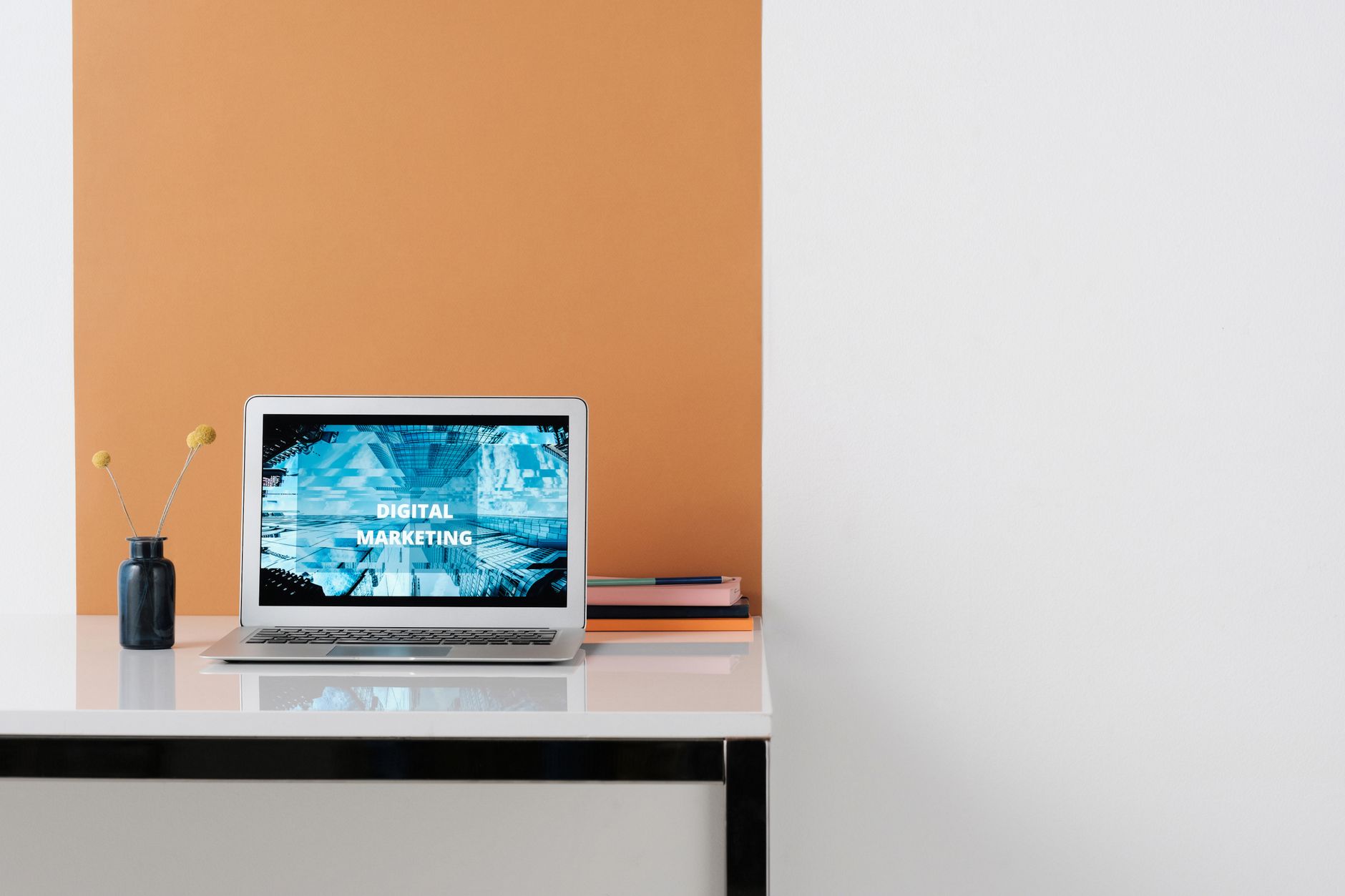 Laptop displaying "DIGITAL MARKETING" on a desk with a vase, symbolizing digital tools for startups