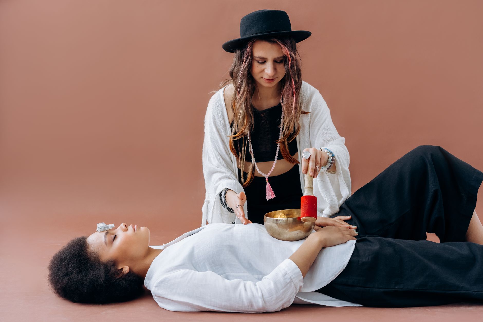 Practitioner uses singing bowl for sound healing during a chakra balancing session