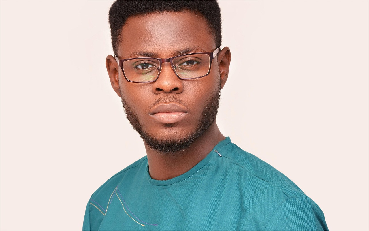 A serious Nigerian man in traditional attire wearing glasses looking ahead