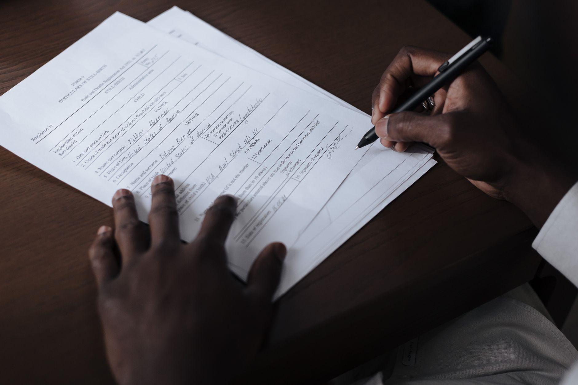 A person's hand writing on a formal document during a title review process