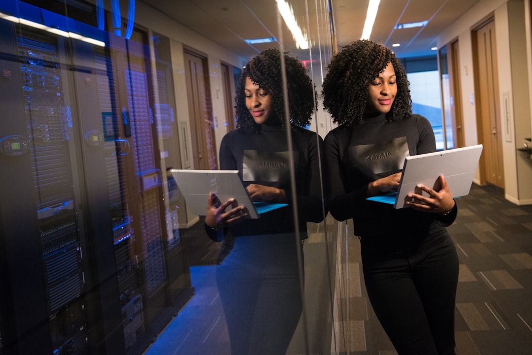 Woman holding a tablet in a server room, reflecting on corporate legal tech