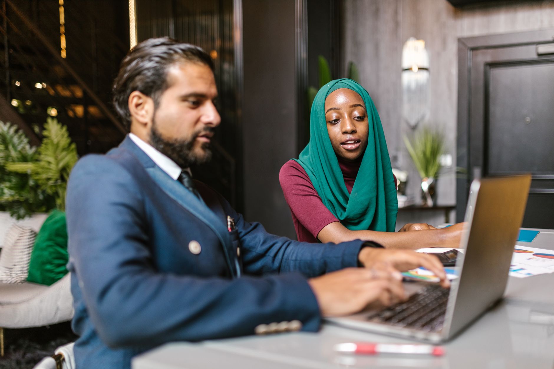 Two professionals, a man and a woman, collaborating on a laptop in an office