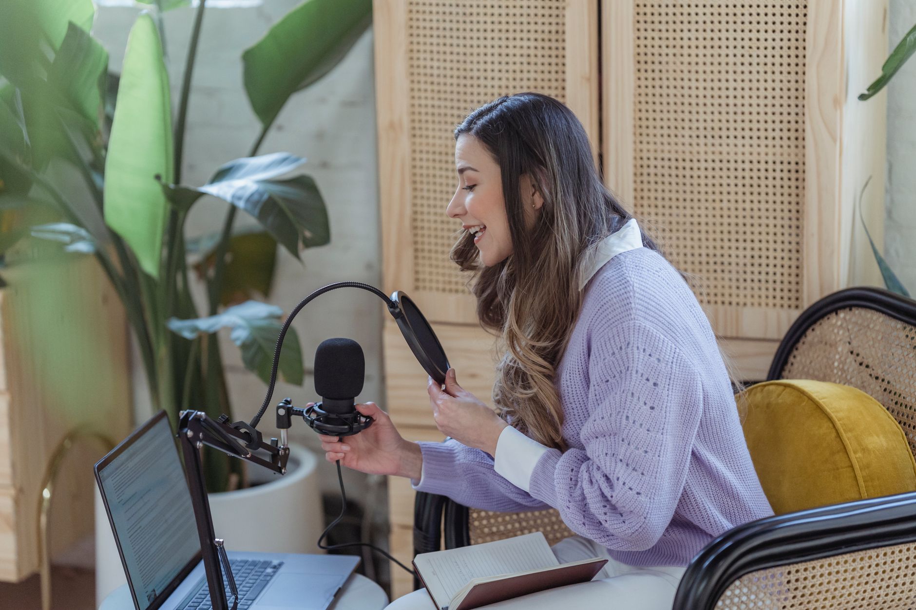 A woman in a purple sweater speaks into a microphone beside a laptop