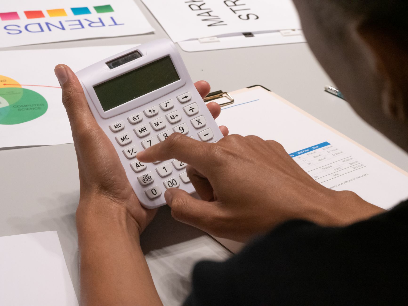 Hands using a calculator to figure event decorator pricing with financial documents