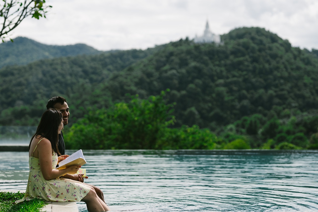 Couple relaxing by an infinity pool with mountains and a distant temple