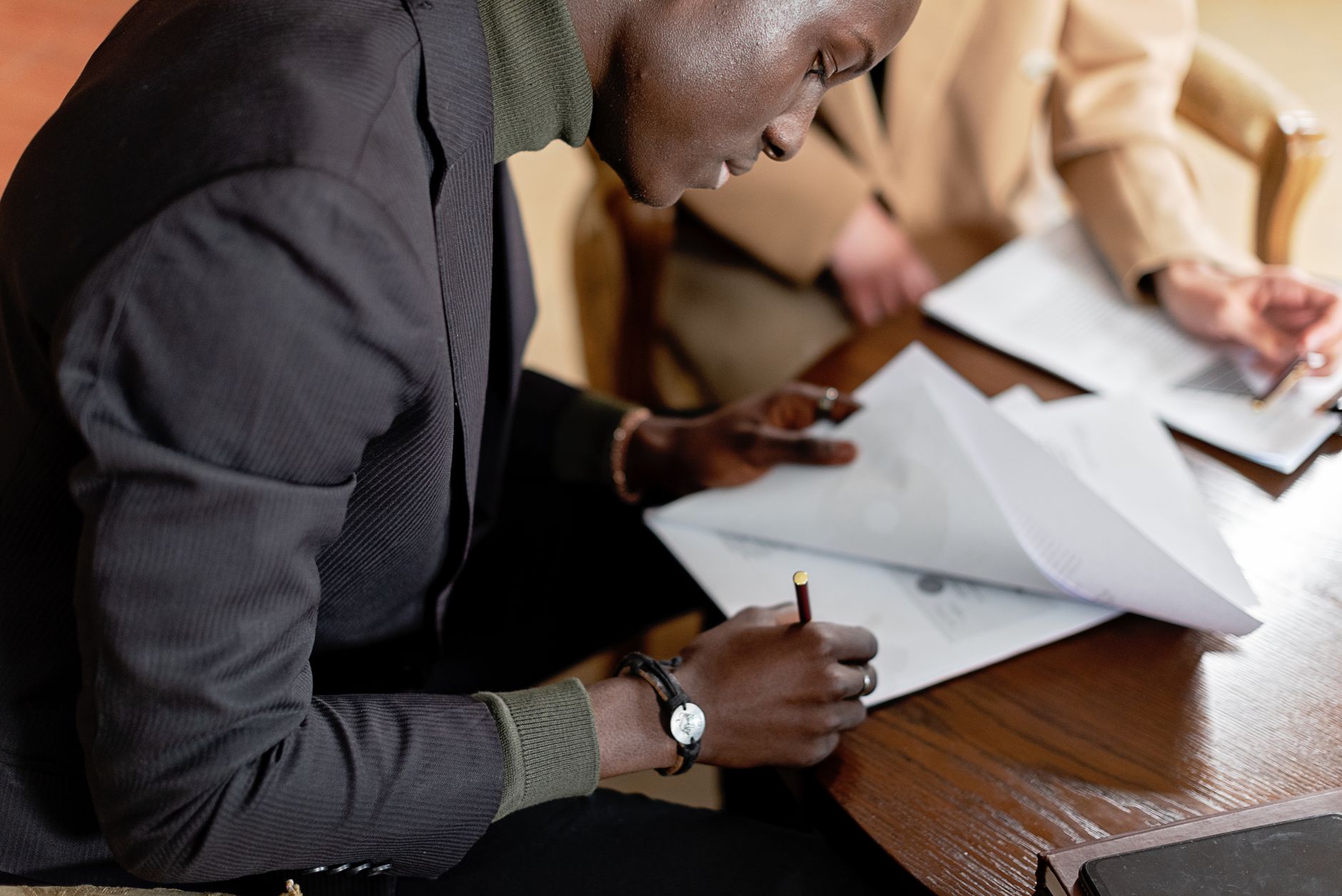 A person in a suit is signing important documents at a desk