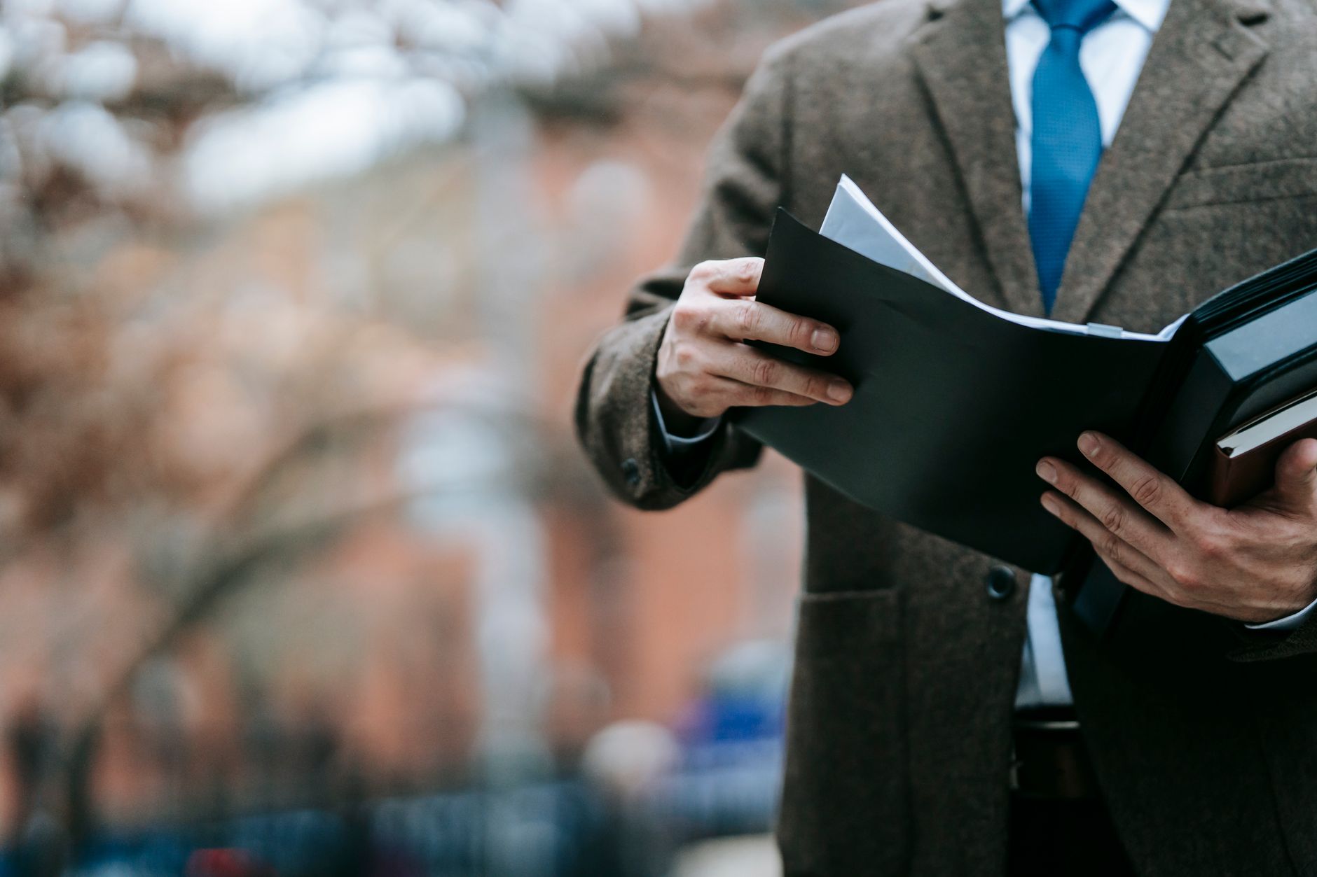 A person in a suit reviews documents in a folder, perhaps for intellectual property