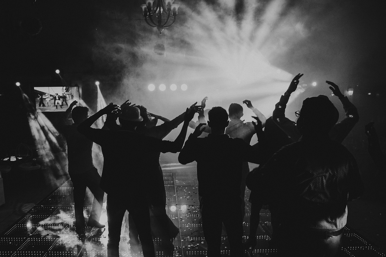 Silhouetted people dance at a lively, modern engagement party with bright lights and smoke