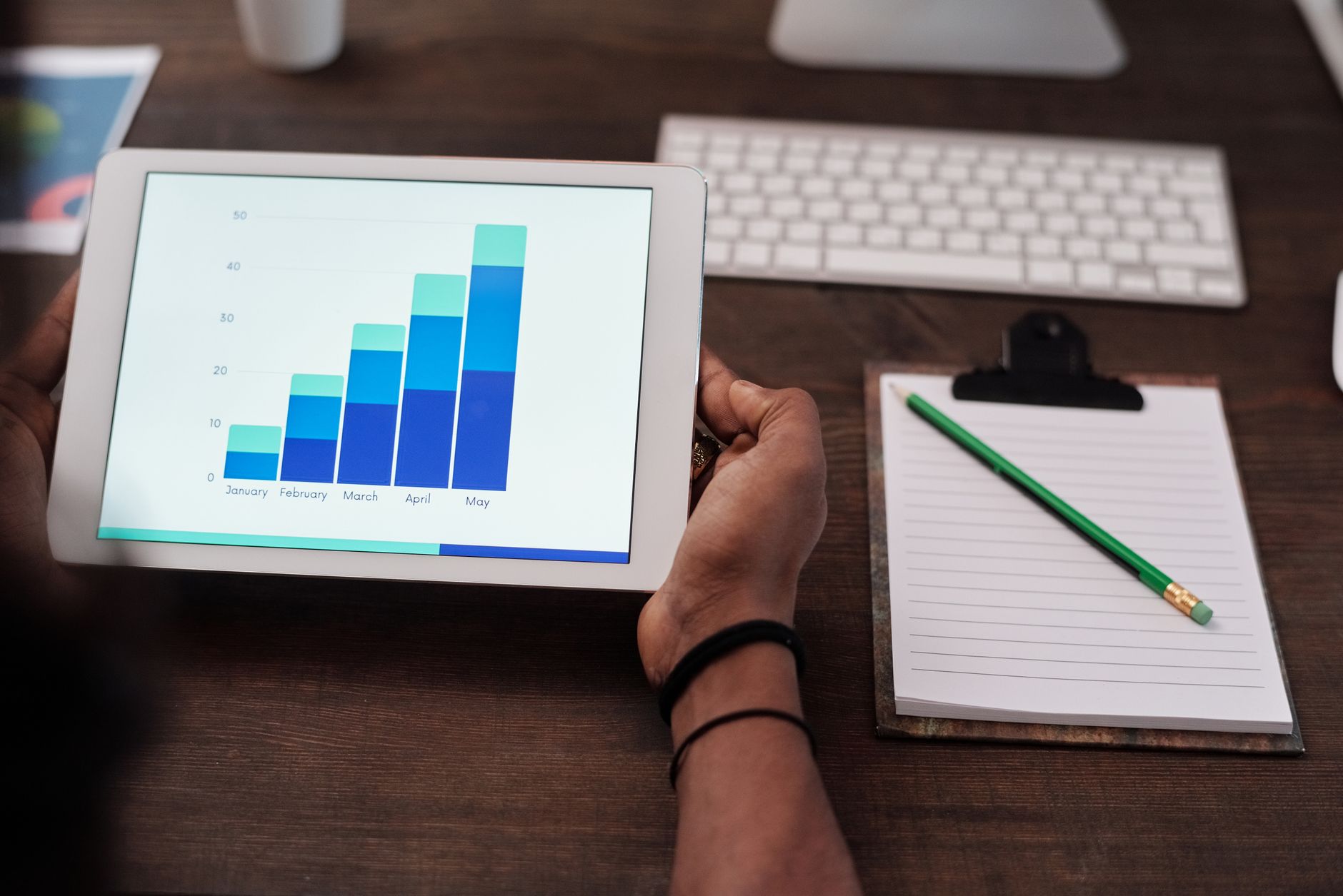 Person holding a tablet showing an upward trending bar chart for SEO performance