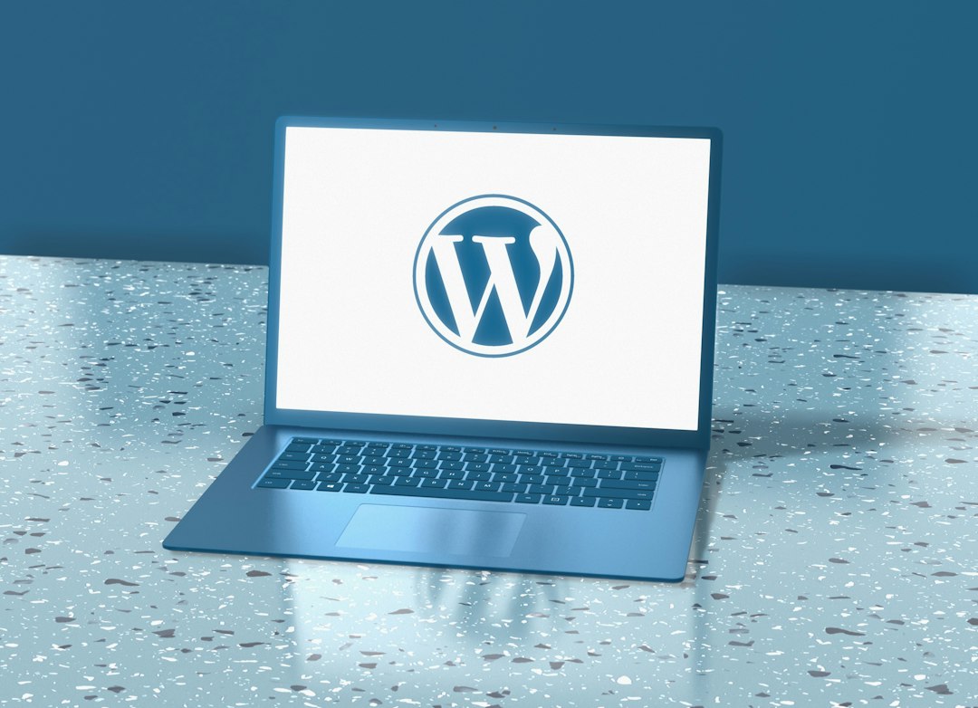 A blue laptop sits on a speckled table displaying the WordPress logo