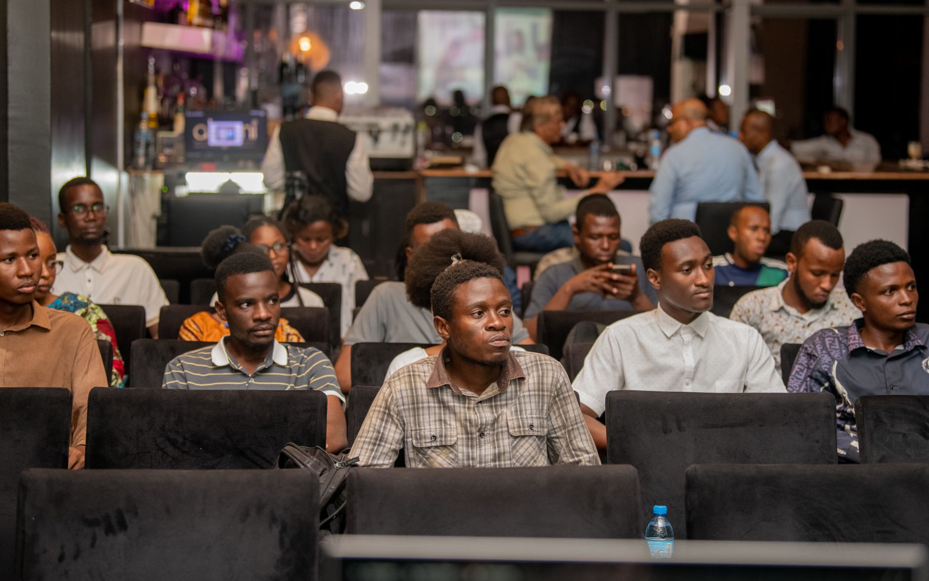 Young adults in an audience attentively watching a presentation at an event