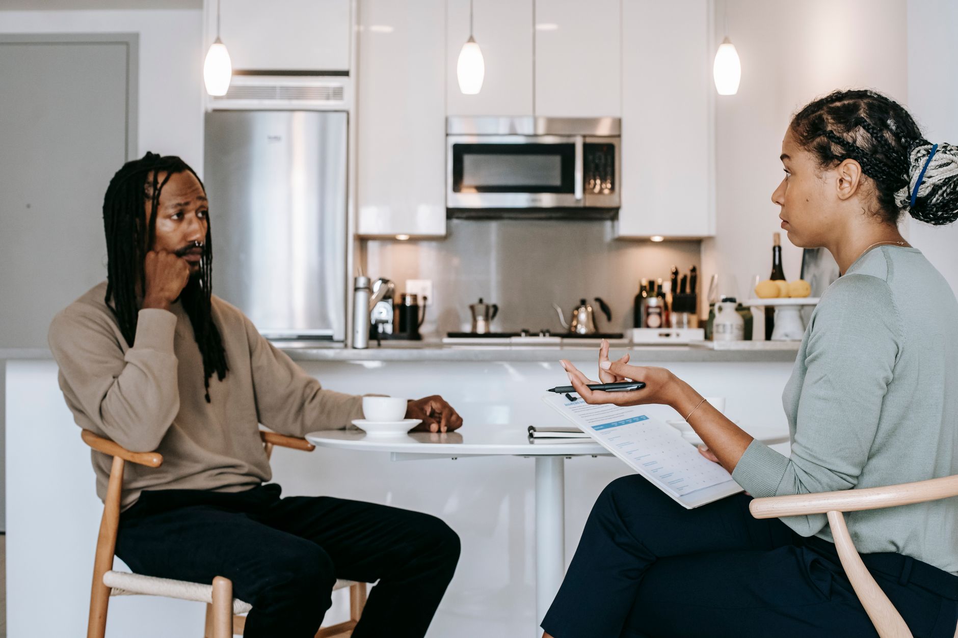 Two people discuss legal matters at a table in a modern kitchen