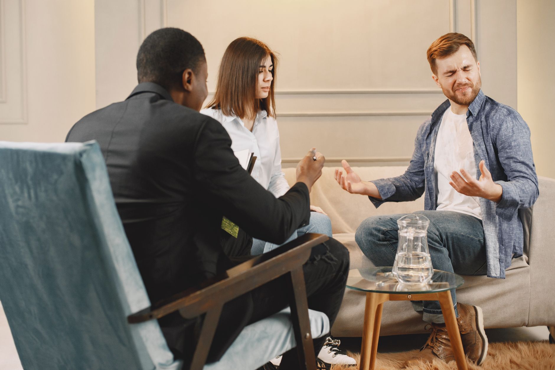 A couple and a lawyer or mediator in a discussion, man looks frustrated